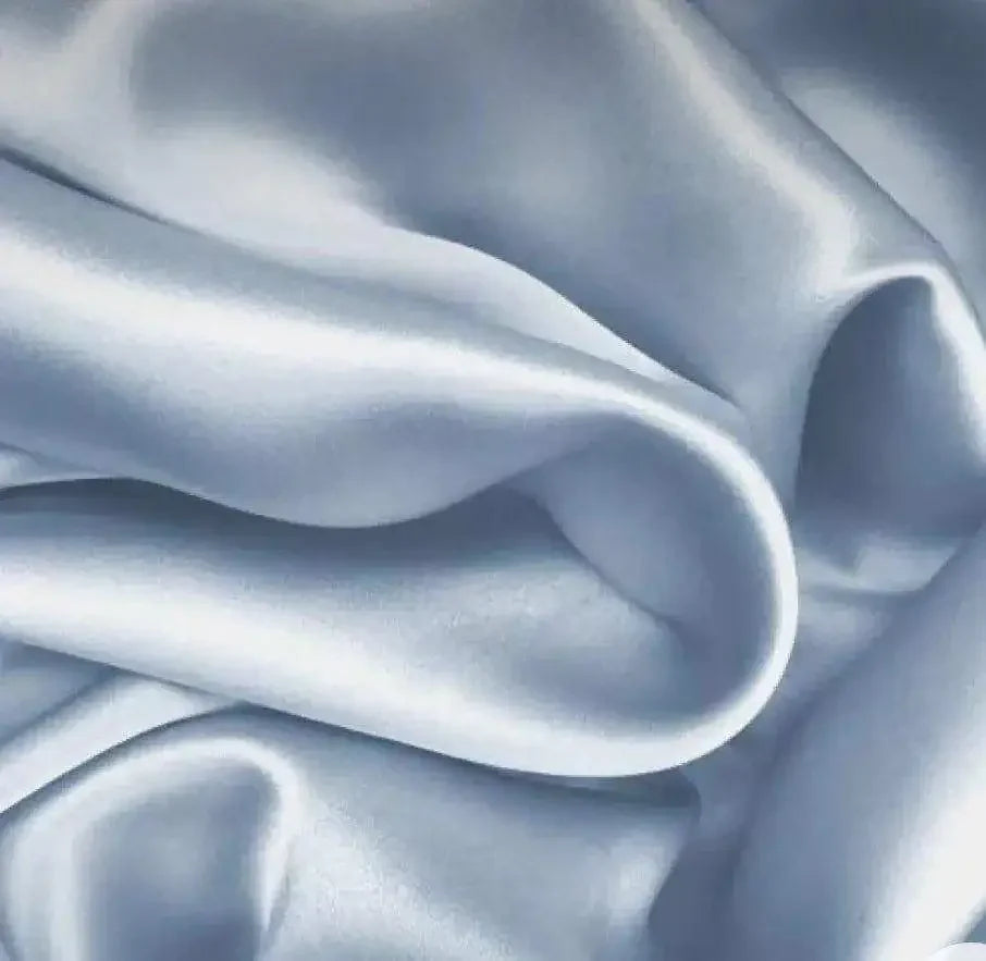 Close-up of smooth, light blue silk fabric with soft folds and a shiny texture