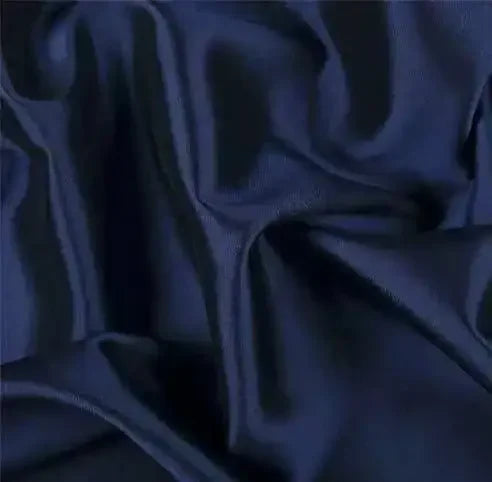 Close-up of navy blue plain silk fabric with smooth, flowing folds and a shiny texture