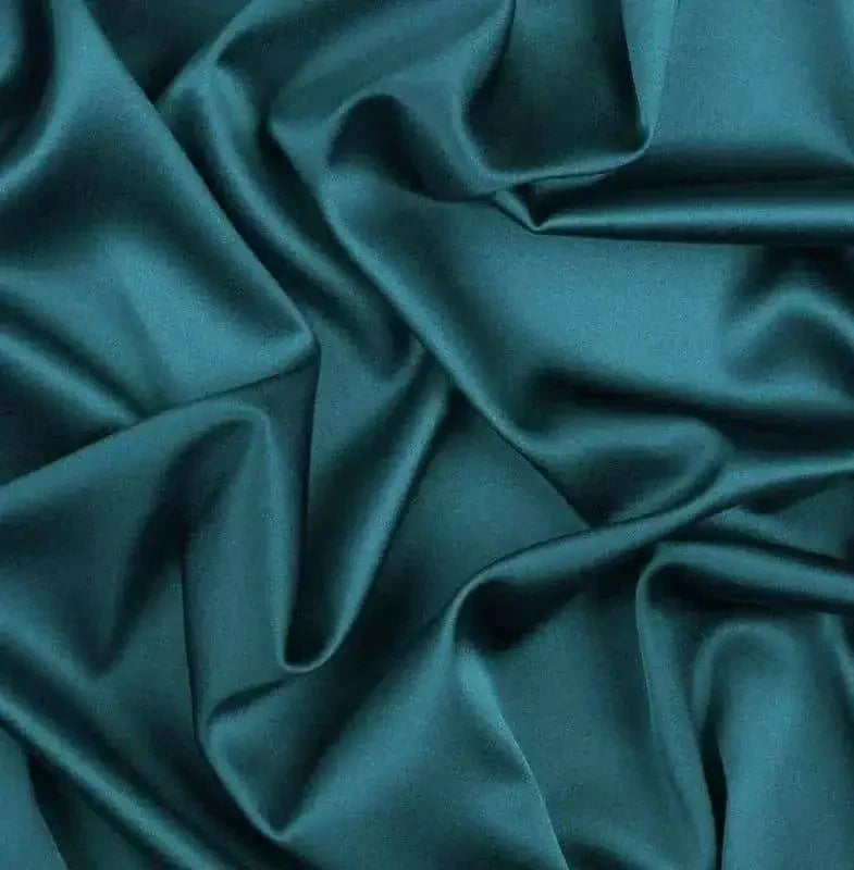 close-up of rich teal smooth plain silk fabric with soft folds and sheen